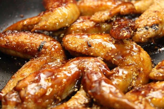 甘辛いタレが塗られた、パリッとした名古屋風手羽先のイラスト。