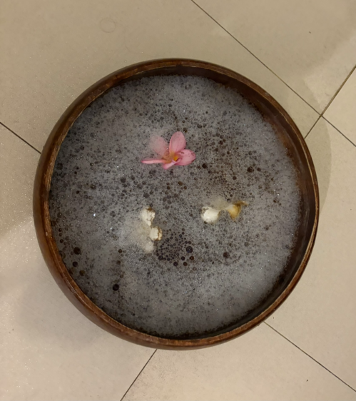 施術前の足湯ボウルに浮かぶピンクと白のお花