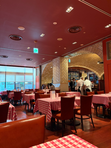 赤い天井とチェック柄のテーブルクロスが特徴的な、広々としたレストランの店内風景。