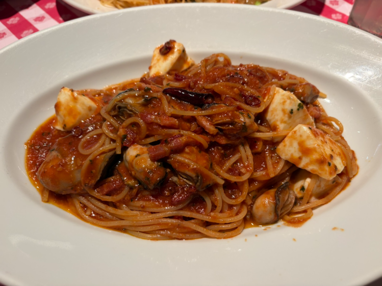 白いお皿に盛られた、大ぶりの牡蠣と角切りモッツァレラチーズが入ったトマトソースパスタ。