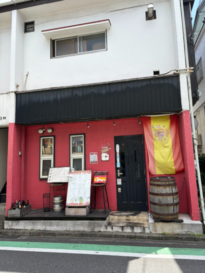 スペイン国旗とワイン樽が飾られた、鮮やかな赤と黒のコントラストが美しいテソロデルマルの外観