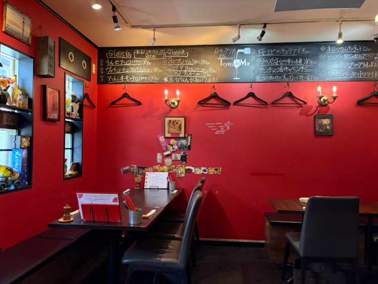 おすすめのワインや料理が白文字でびっしりと書かれた、店内の大きな黒板メニューと赤い壁の客席