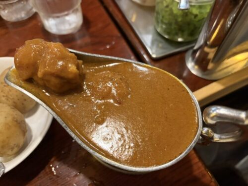 神保町ボンディのチキンカレー、スプーンに乗った大きな鶏肉のアップ