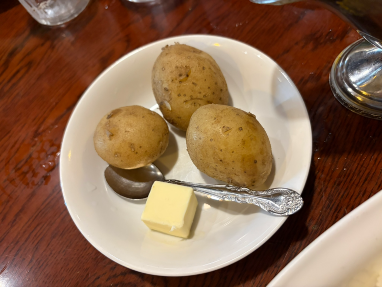 カレーの前に提供される、バターとスプーンが添えられた丸ごとの蒸かしじゃがいも