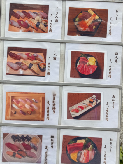 鮨わたせ店頭のメニュー看板。にぎり1人前、1.5人前、ちらし、鉄火丼などの写真と価格。