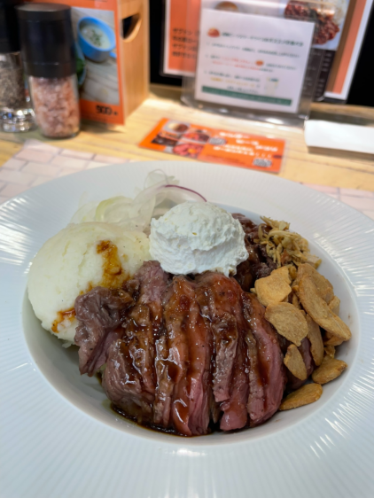 センタービーフのステーキライス。白い皿に盛られたレア焼きのビーフステーキ、マッシュポテト、ホイップバター、ガーリックチップ。