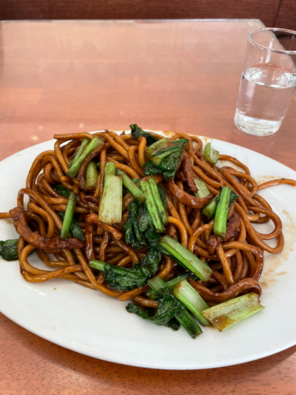 萬来亭（まんらいてい）の名物上海焼きそば。濃い醤油色の極太麺に緑の青菜が和えられた一皿。