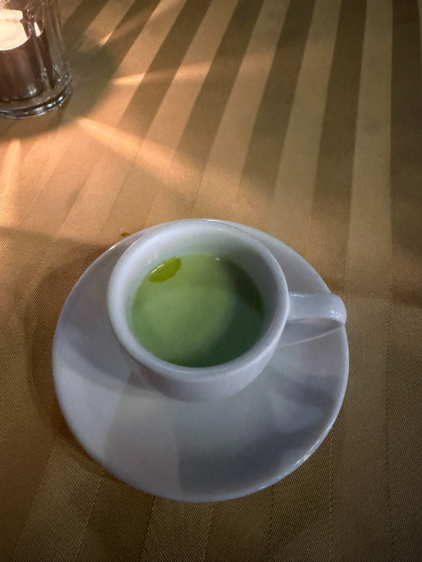 白いカップに入った、鮮やかなグリーンの冷製スープ。中央にはクリームのようなものが浮いている。